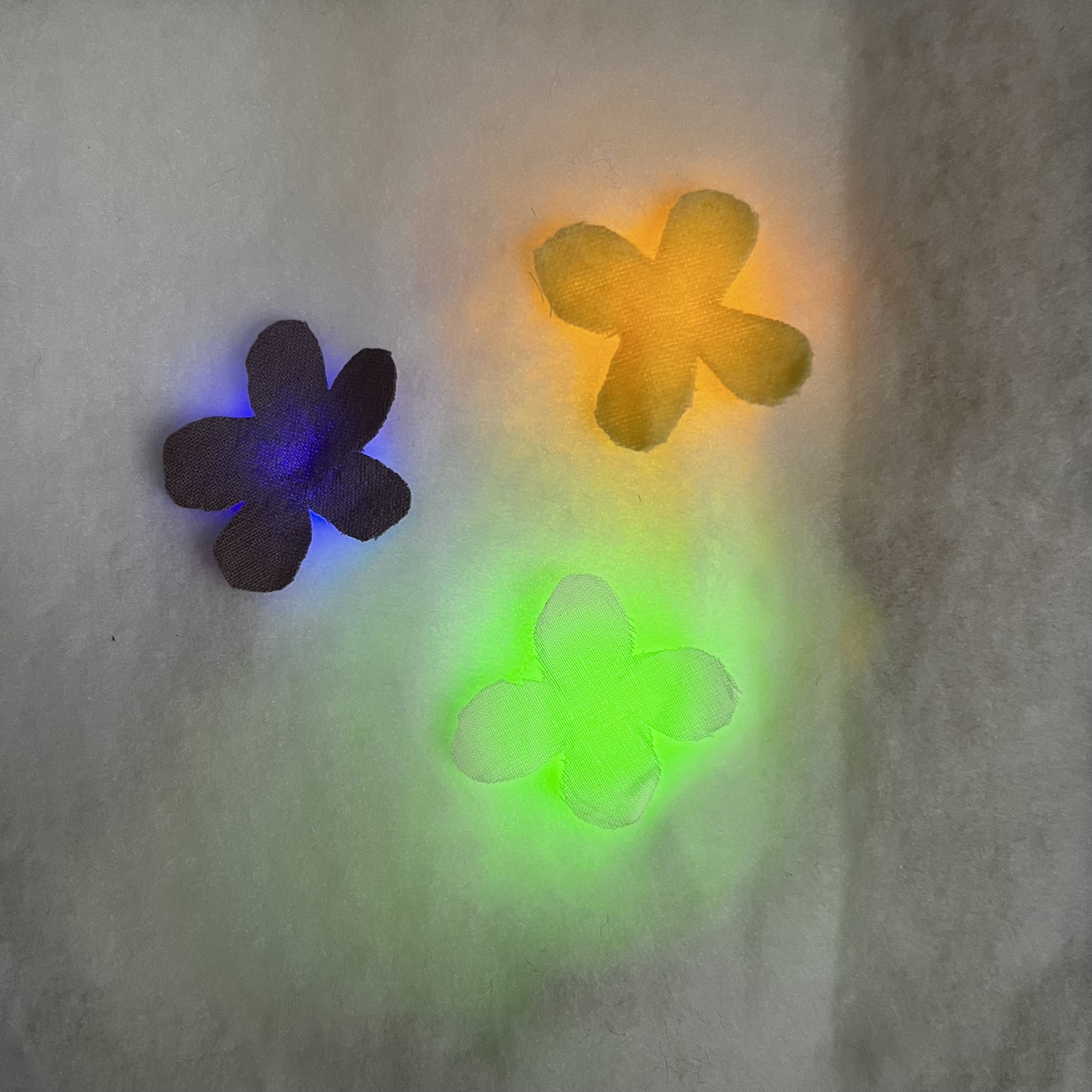 Fabric flowers on top of fabric that gives off a glowing effect to the flowers